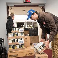 Students lift boxes of cans at a food pantry.